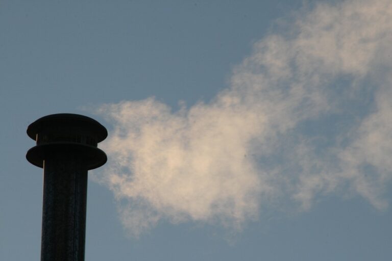 Chimney billowing smoke against blue sky