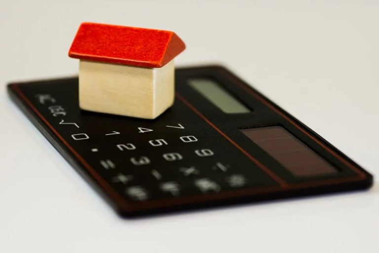 Wooden house on top of black calculator