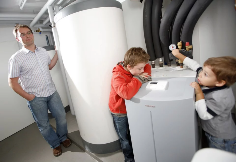 Two boys looking at a heat pump supervised by their father