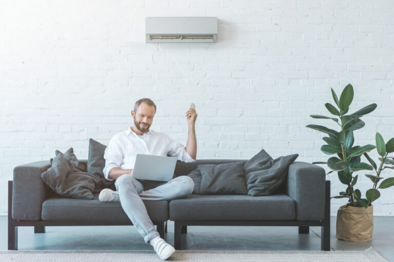 man-working-on-laptop-while-sitting-on-grey-couch