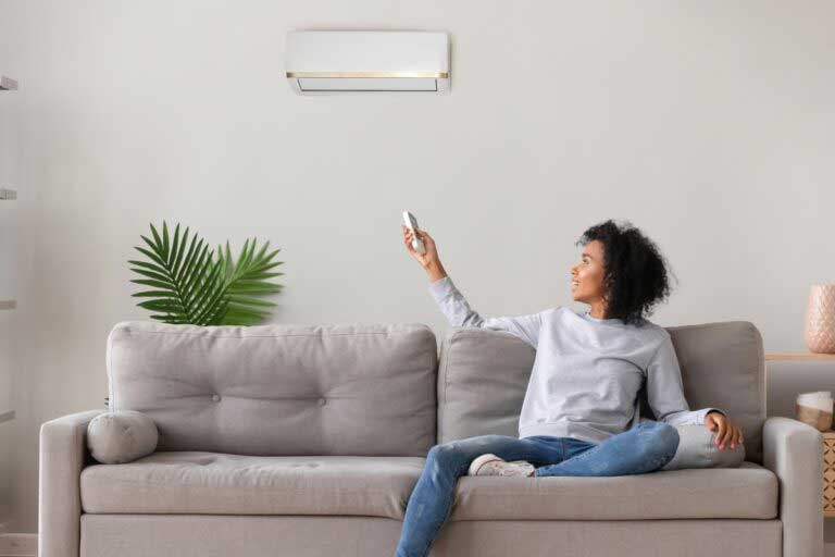 person sitting on couch using new air conditioner on wall